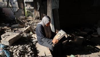 نازحة فلسطينية وسط الأنقاض تتأمل صورة والدها