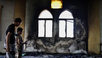 فلسطينيان يتفحصان المسجد المحترق