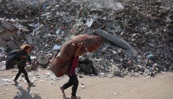 طفلان في غزة يحملان أمتعتهما أمام صاروخ لم ينفجر 