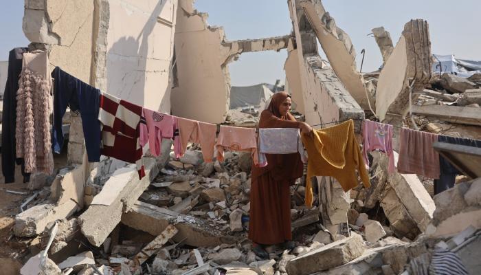 فلسطينية تنشر ملابسها وسط الأنقاض في غزة