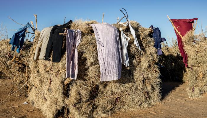 ملابس معلقة في مأوى من القش للاجئين سودانيين