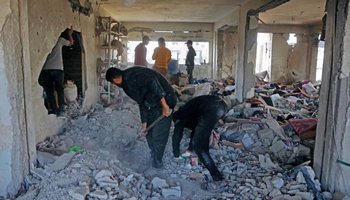 فلسطينون وسط أنقاض أحد المنزل بغزة - أ.ف.ب