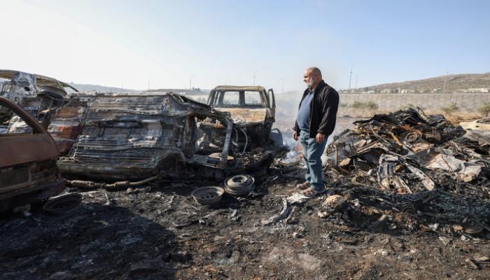 فلسطيني يتفقد سيارات عقب هجوم مستوطنين