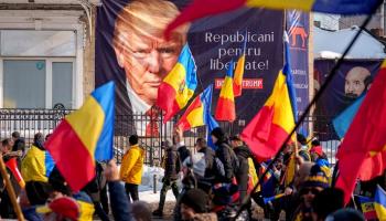أنصار كالين جورجيسكو يسيرون أمام لافتة دونالد ترامب