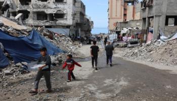 فلسطينيون يسيرون بين أطلال منازل في غزة