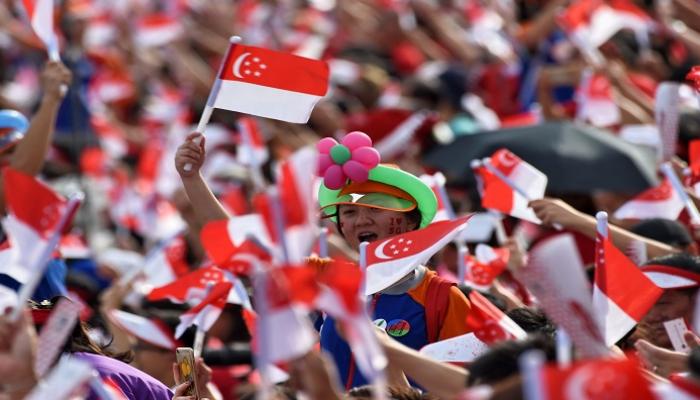 مواطنون سنغافوريون يرفعون علم بلادهم