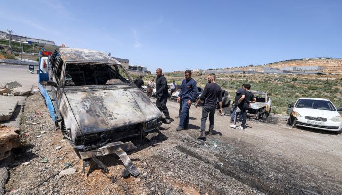 فلسطينيون يتفقدون مركبات أشعل فيها مستوطنون النار قرب سلفيت