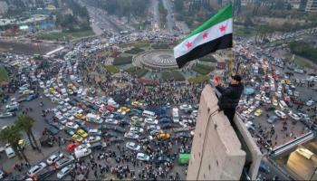 شاب يرفع العلم السوري الجديد في ميدان رئيسي في دمشق 