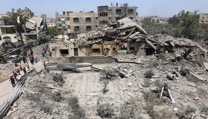 فلسطينيون يتفقدون أنقاض منزل في حي التفاح بغزة