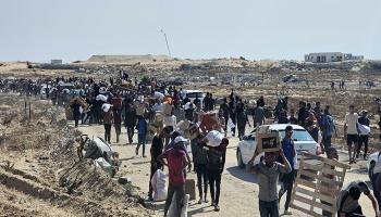 يسير فلسطينيون نازحون على طول الطريق لتلقي طرود مساعدات إنسانية في رفح