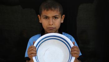 صبي فلسطيني يحمل طبقا فارغا في النصيرات