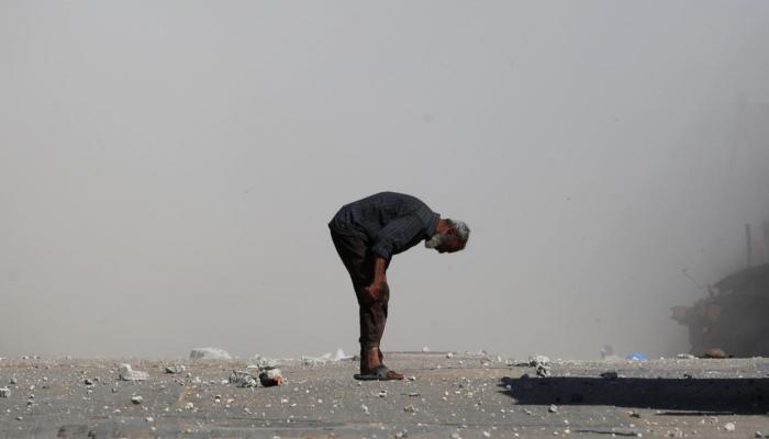 فلسطيني يفحص نفسه بحثًا عن جروح بينما يتصاعد الدخان بعد غارة إسرائيلية