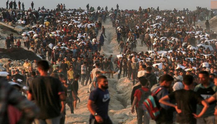 فلسطينيون يحملون أكياس الدقيق على طول شارع الرشيد غرب جباليا
