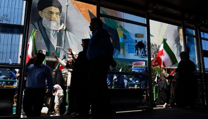 متظاهرون يسيرون تحت جدارية للمرشد الأعلى الإيراني علي خامنئي،