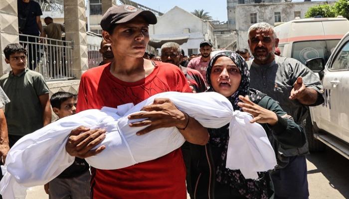 شاب يحمل جثمان طفل قُتل في غارة إسرائيلية