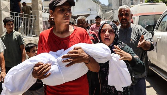 شاب يحمل جثمان طفل فلسطيني قتل في غارة إسرائيلية