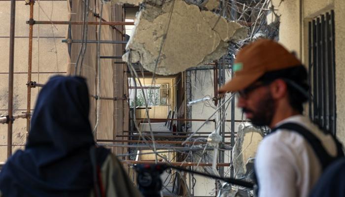 شاب وفتاة في إيران أمام مبنى متضرر جراء القصف الإسرائيلي