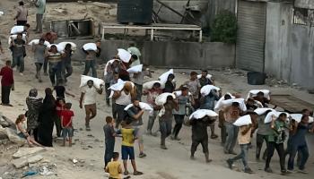 فلسطينيون يحملون أكياس الدقيق في خان يونس