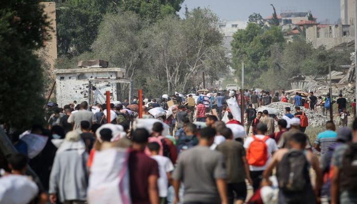 فلسطينيون في مخيم النصيرات يحملون طرودًا غذائية 