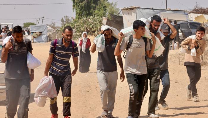 فلسطينيون يحملون مساعدات تلقوها في معبر رفح