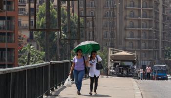 امرأتان تحتميان بمظلة من أشعة الشمس على أحد الجسور في القاهرة- أرشيفية