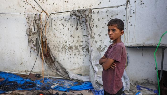 طفل فلسطيني بغزة بجوار حائط عليه آثار الرصاص - أ.ف.ب