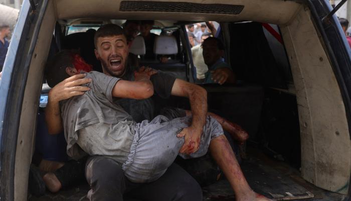 فلسطيني يحمل طفلا مصابا في غزة