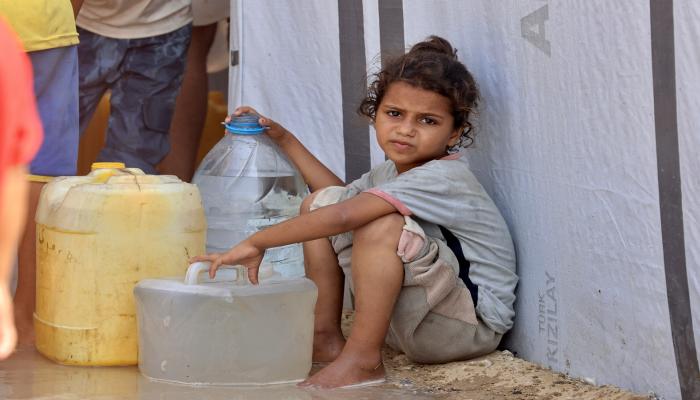 طفلة فلسطينية تملأ زجاجات مياه في غزة