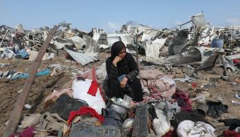 نازحة فلسطينية تجلس على أنقاض مخيم في دير البلح