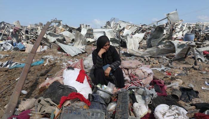 نازحة فلسطينية تجلس على أنقاض مخيم في دير البلح