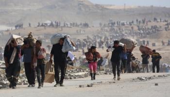 فلسطينيون يحملون أكياسًا من المساعدات الإنسانية قرب ممر نتساريم