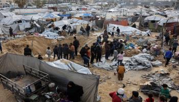 فلسطينيون يتفقدون موقع غارة إسرائيلية على مخيم خيام يؤوي نازحين في غزة