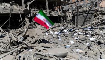 علم إيران أمام مبنى مدمر