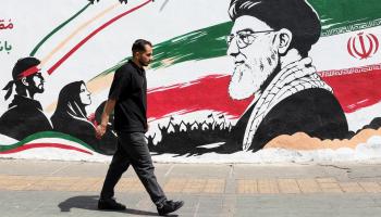رجل يمر أمام جدارية عليها صورة علي خامنئي في طهران