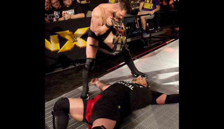 فين بالور يمسك حزام البطولة بينما ساموا جو ملقى على الأرض