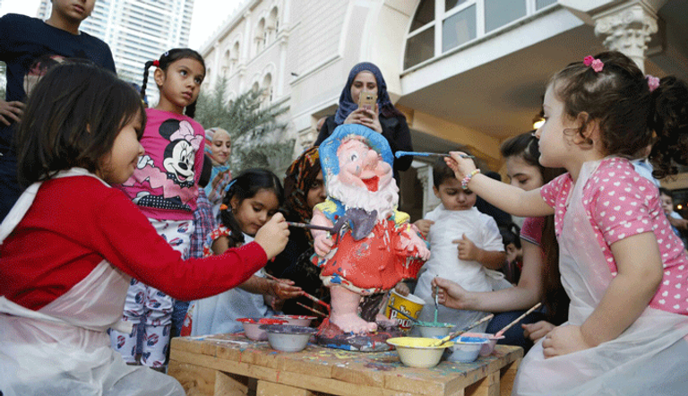 أطفال يشاركون في فعالية تلوين المجسمات السيراميكية في مهرجان القصباء