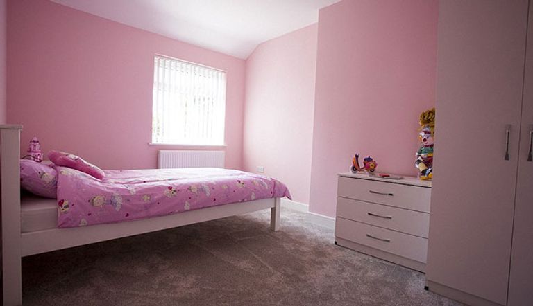 إحدى غرف النوم في المنزل تم تزويدها بأثاث جديد، و سجادة باللون الوردي