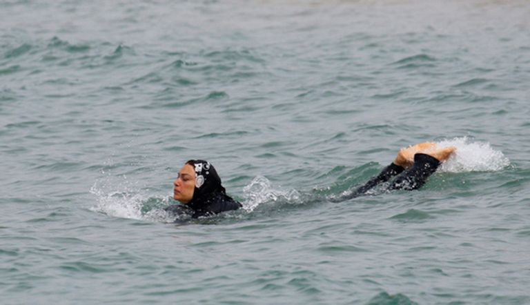 امرأة مسلمة ترتدي البوركيني وهي تسبح في البحر بمدينة مرسيليا الفرنسية (رويترز)