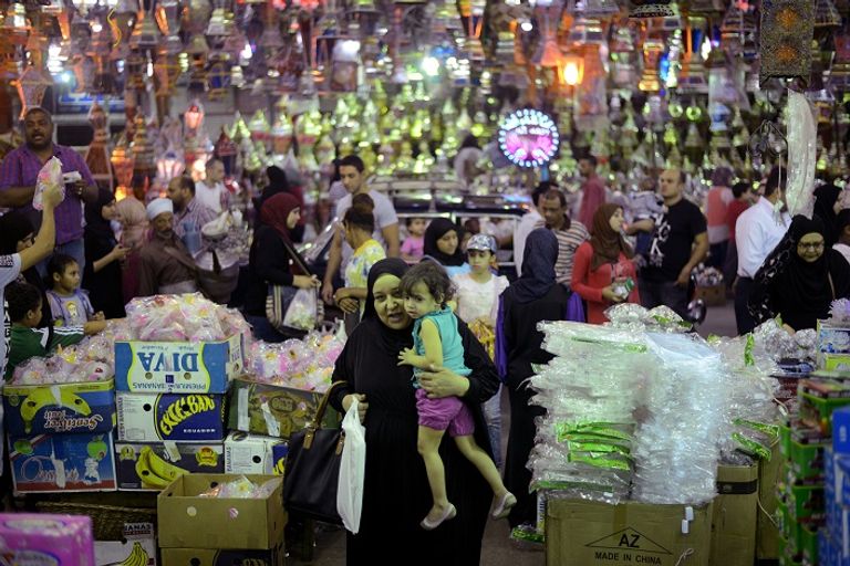 سيدة مصرية تحمل طفلها في سوق شعبي (أ ف ب)