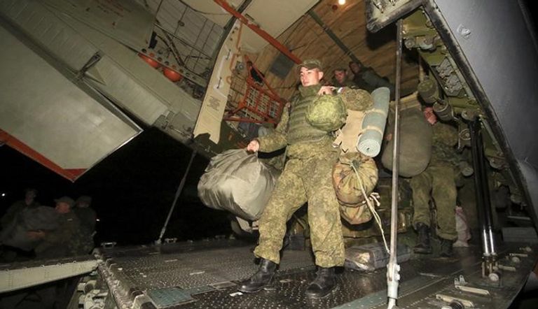 أفراد في قاعدة جوية روسية في سوريا وهم يحملون معدات على متن طائرة نقل لإعادتها إلى روسيا