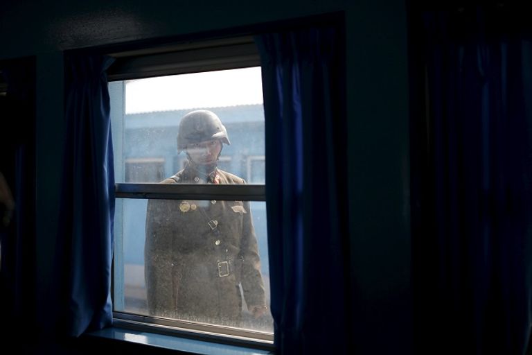 جندي كوري شمالي ينظر إلى داخل غرفة على الحدود مع كوريا الجنوبية (رويترز)