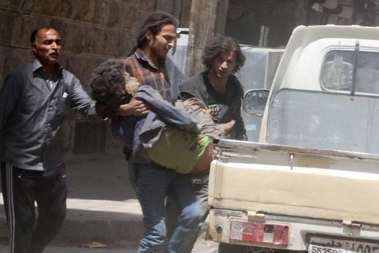 رجل يحمل طفلا مصابا في ضربة جوية بمنطقة تسيطر عليها المعارضة السورية في حلب - رويترز