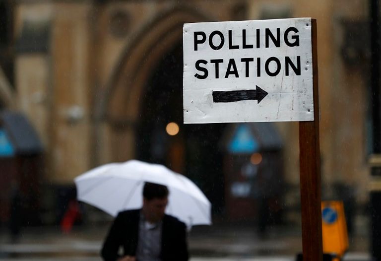 بريطاني يسير بجوار مركز للاقتراع في لندن (رويترز)