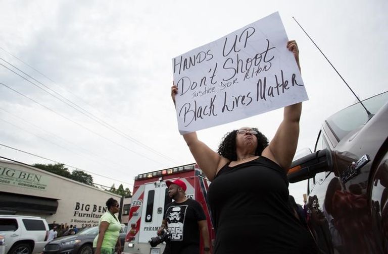 امراة ترفع لافتة اثناء احتجاج ضد تعامل الشرطة مع السود في باتون روج بولاية لويزيانا الأمريكية - رويترز