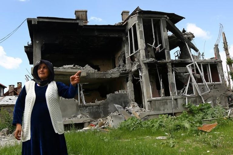 امرأة تقف امام منزل دمر جراء الاشتباكات بين القوات التركية والأكراد في جنوب شرق تركيا - رويترز