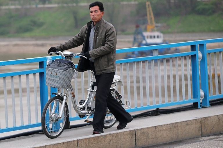 كوري شمالي يدفع دراجة كهربائية في أحد شوارع بيونج يانج (رويترز)