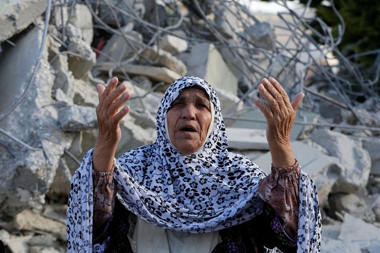 سيدة فلسطينية تقف أمام منزلها بعد تحطيمه في أحد الغارات الإسرائيلية