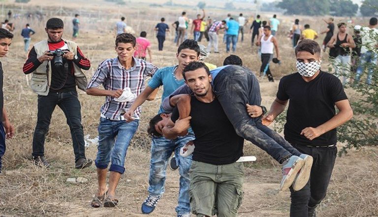 شبان فلسطينيون ينقلون جريحًا في مواجهات مع الجيش الإسرائيلي شرق البريج