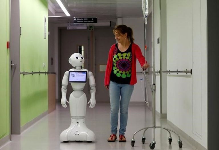 امرأة تسير مع إنسان آلي في مستشفى ببلجيكا.. فمن يساعد من؟