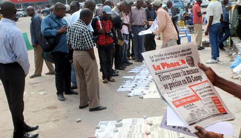 مواطنون يقرأون عناوين الصحف لدى بائع للصحف في كينشاسا